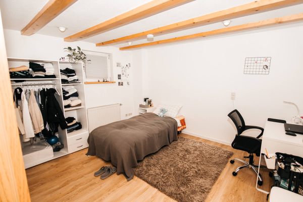 Einladendes Schlafzimmer mit Holzbalken und Schreibtisch im Studentenwohnheim City in Furtwangen