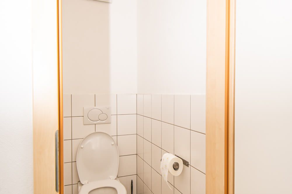 Einzelne Toilettenkabine mit Spiegel und Beleuchtung im Studentenwohnheim Solar