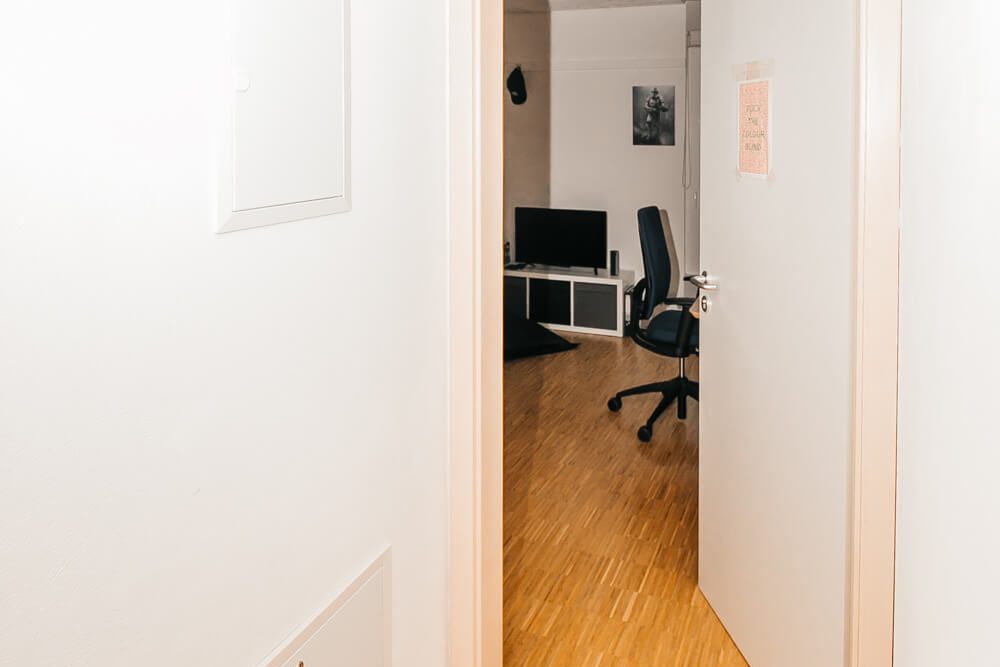 Blick in den Flur mit Holzboden führend zu einem Zimmer im Studentenwohnheim Solar